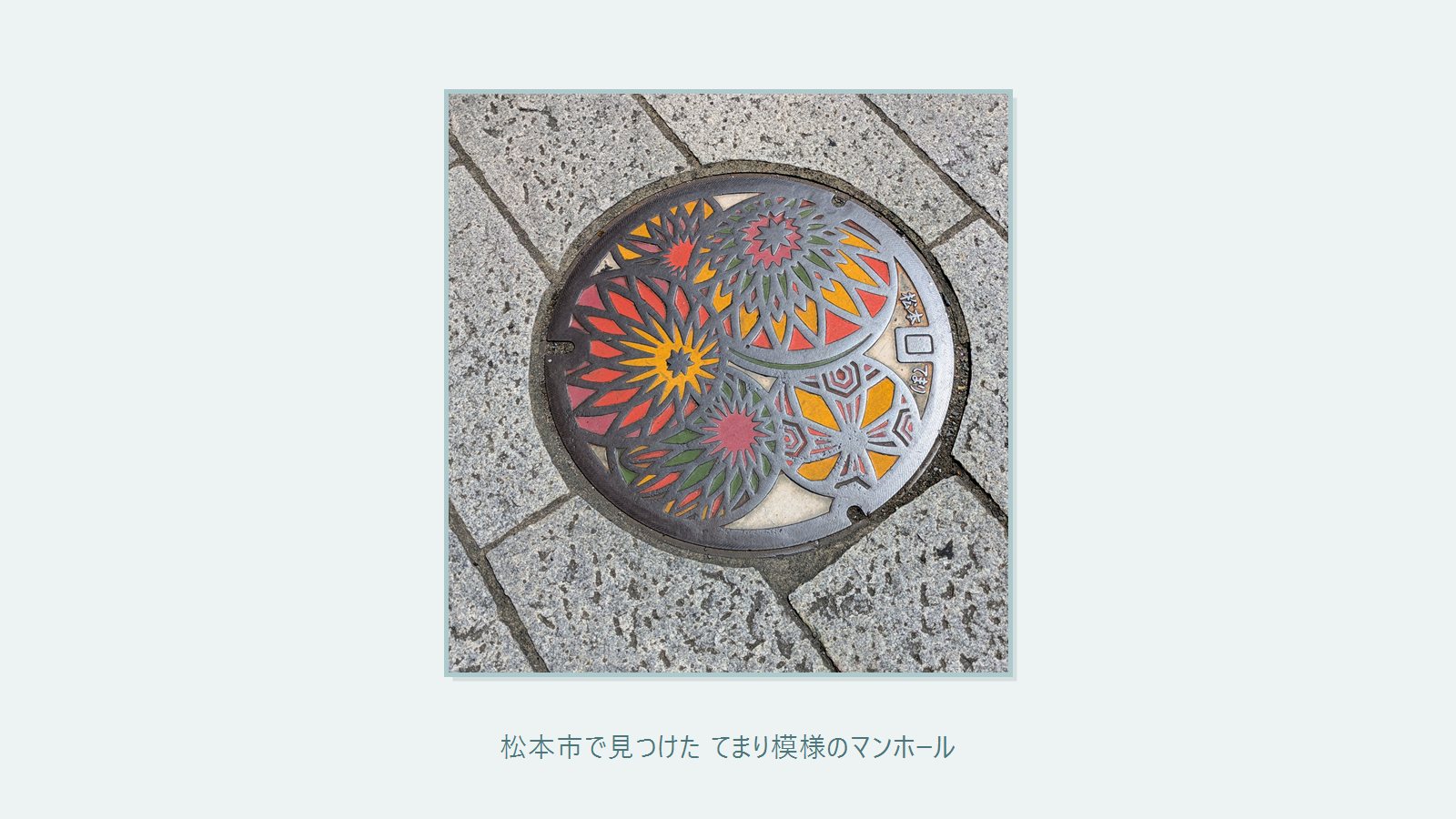 松本市の歩道に設置された松本てまり柄のマンホール蓋 赤や黄や緑の鮮やかな配色で大小の円が重なり合う